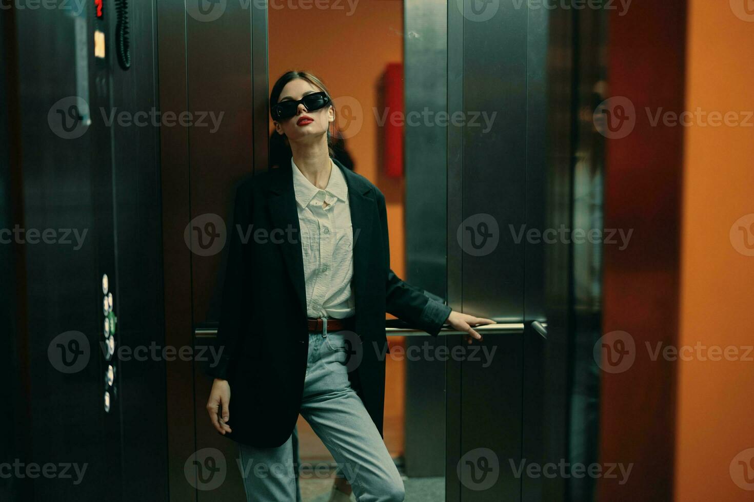 elegante mujer en negro chaqueta y Gafas de sol posando en ascensor, Moda modelo, oscuro cinematográfico ligero y color, glamour Clásico foto