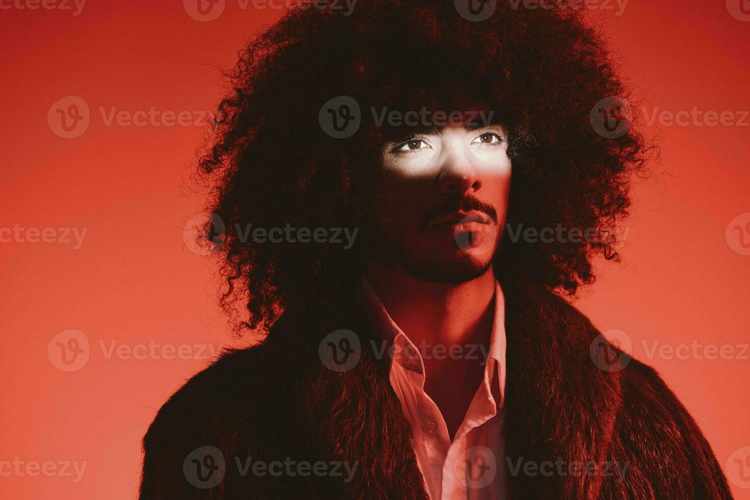 Fashion portrait of a man with curly hair on a red background, multinational, colored light, trendy, modern concept. photo