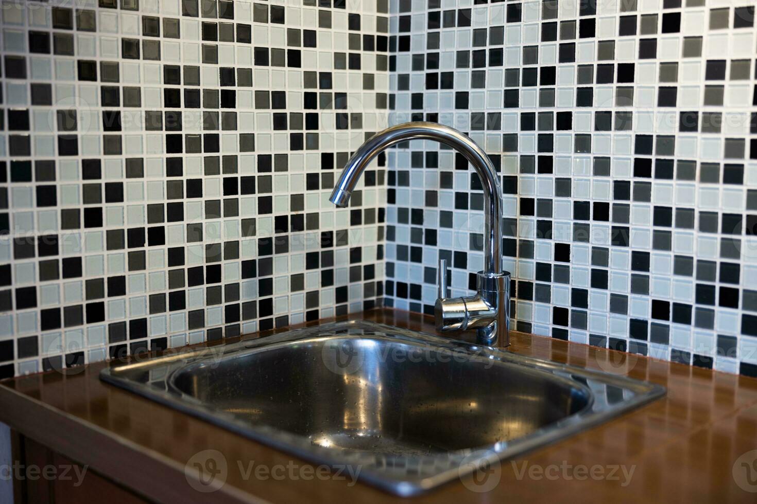 Clean sink with pouring water in the kitchen, metal faucet and sink in an old home interior. photo