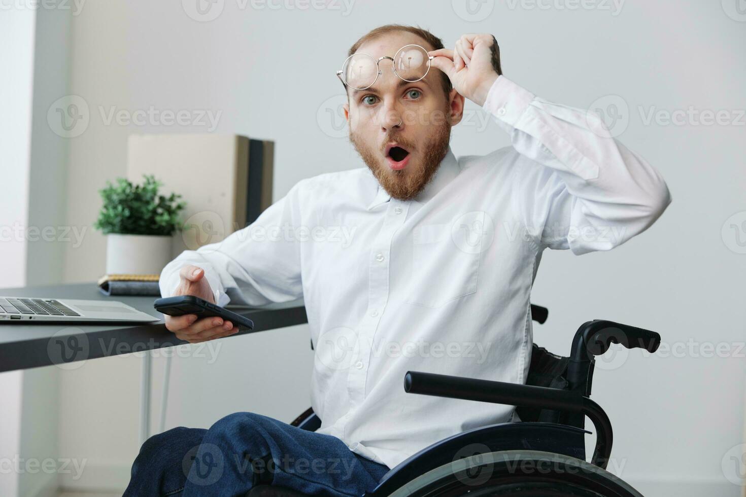 A man in a wheelchair in the office works at a laptop, work online, social networks and startup, copy space, integration into society, concept of health disabled person, real person close-up photo