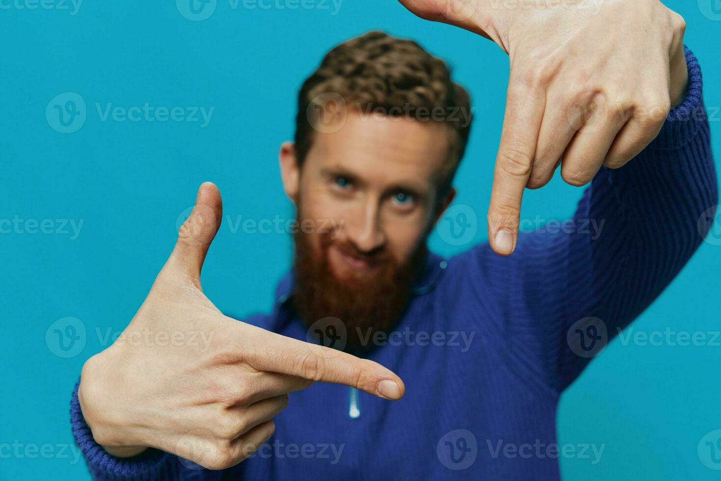 Portrait of a man in a sweater smile and happiness, hand signs and symbols, on a blue background. Lifestyle positive, copy place. photo