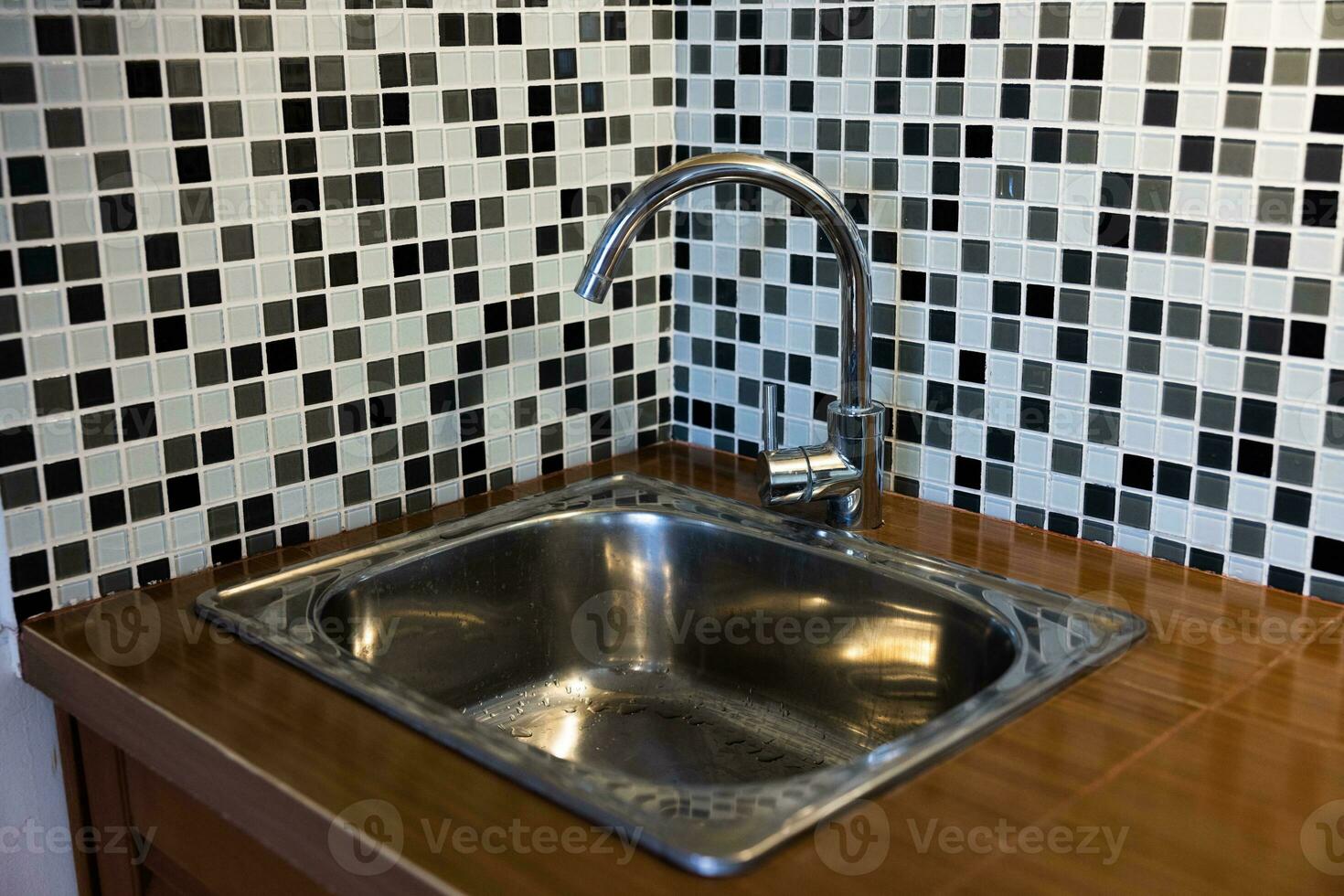 Clean sink with pouring water in the kitchen, metal faucet and sink in an old home interior. photo