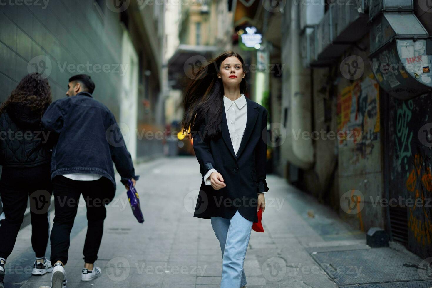 Moda mujer turista en elegante ropa en un chaqueta y rojo boina caminando abajo un estrecho ciudad calle volador pelo y contento viajar, francés estilo, cinematográfico color, retro estilo. foto