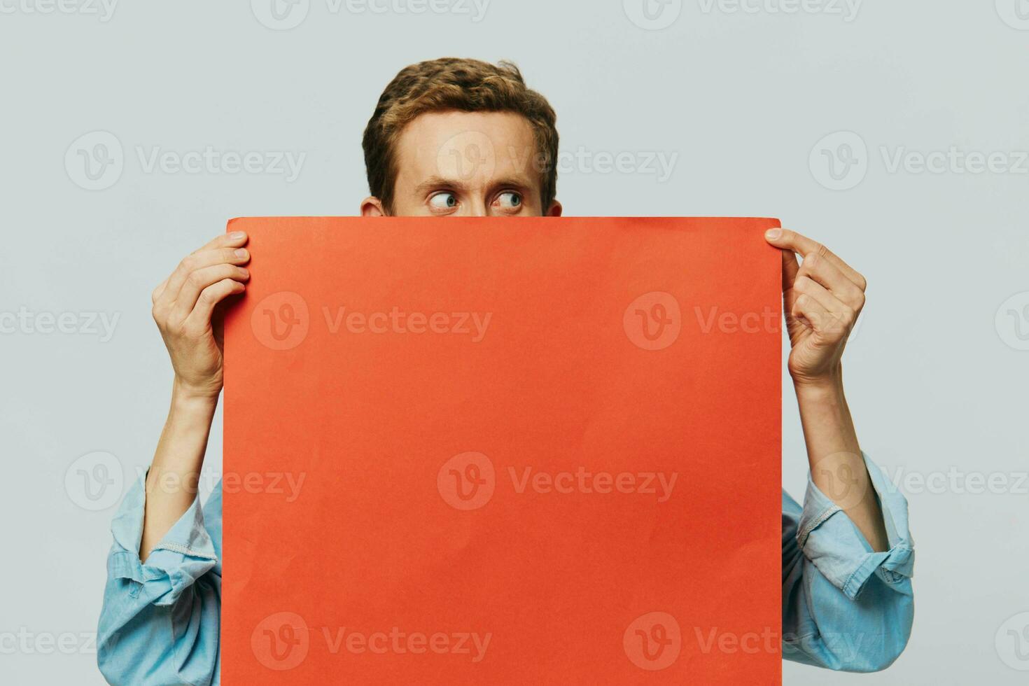 Portrait of an adult male on a gray background with a red piece of paper for your design and text, layout, copy space, space for text photo