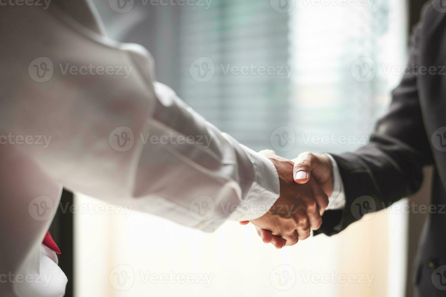 Close up of two business people shaking hands while sitting at the working place photo