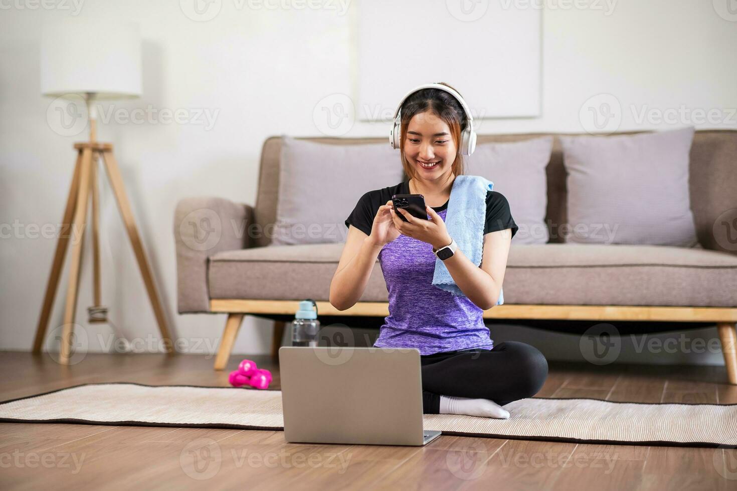 Asian woman in sports wear enjoy doing workout at home with smart phone or laptop. home exercise concept. photo