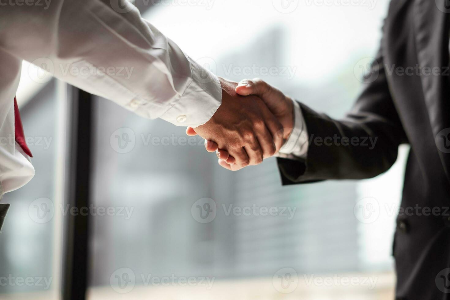 Close up of two business people shaking hands while sitting at the working place photo