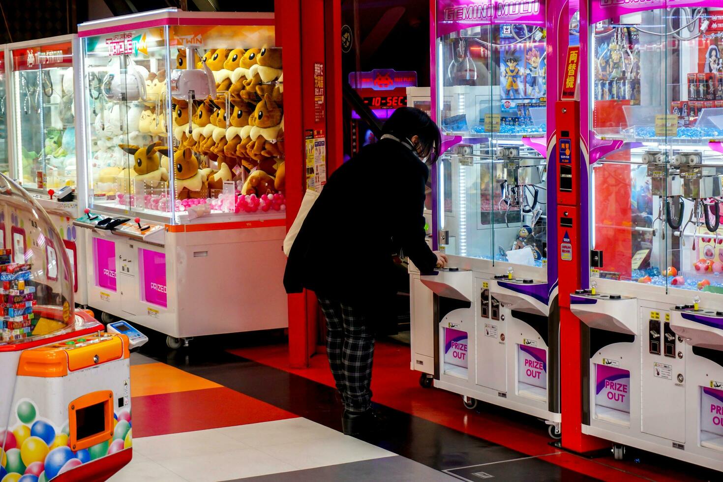 Osaka, Japan, 2019- Japanese girl playing dolls cabinet catches machine intently in game shop. Dolls cabinet catches is a coins operated entertainment machine, Popular in Japan and Asia. photo