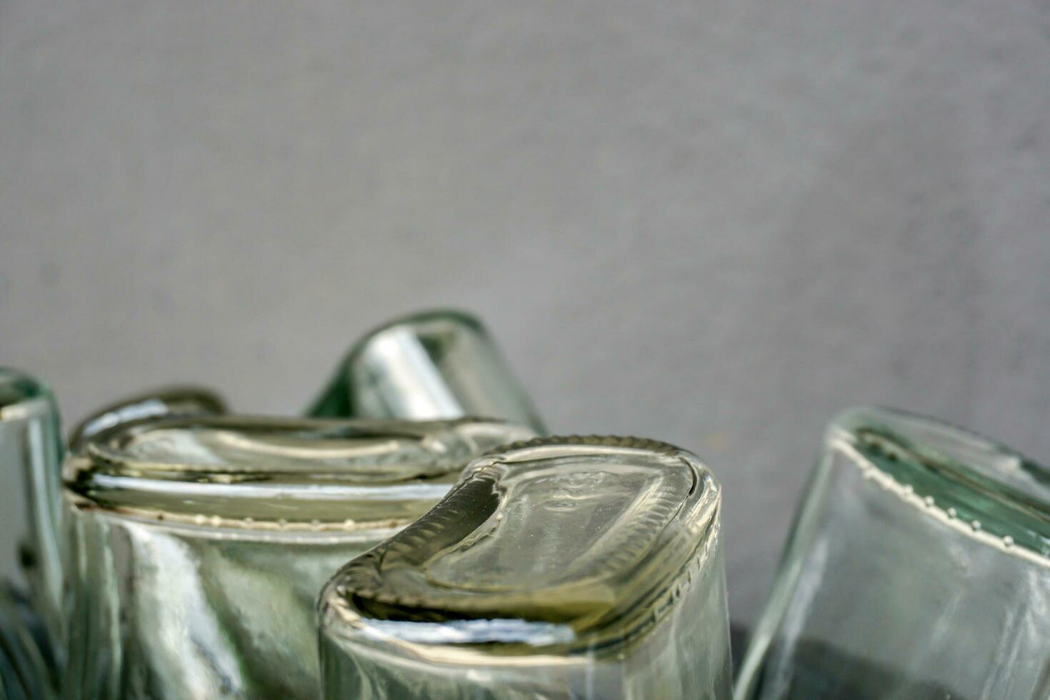 Closeup and crop of up side down and bottom of flat glass bottle on blurred gray background. photo