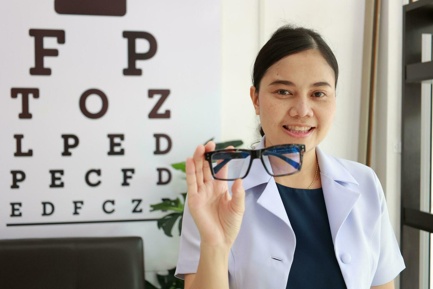 Female ophthalmologist holding eyeglasses inside clinic, eye doctor holding glasses in eyeglasses shop, Ophthalmologist holding eyeglasses in eyeglass clinic photo