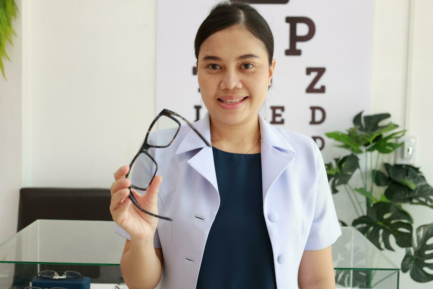 Female ophthalmologist holding eyeglasses inside clinic, eye doctor holding glasses in eyeglasses shop, Ophthalmologist holding eyeglasses in eyeglass clinic photo