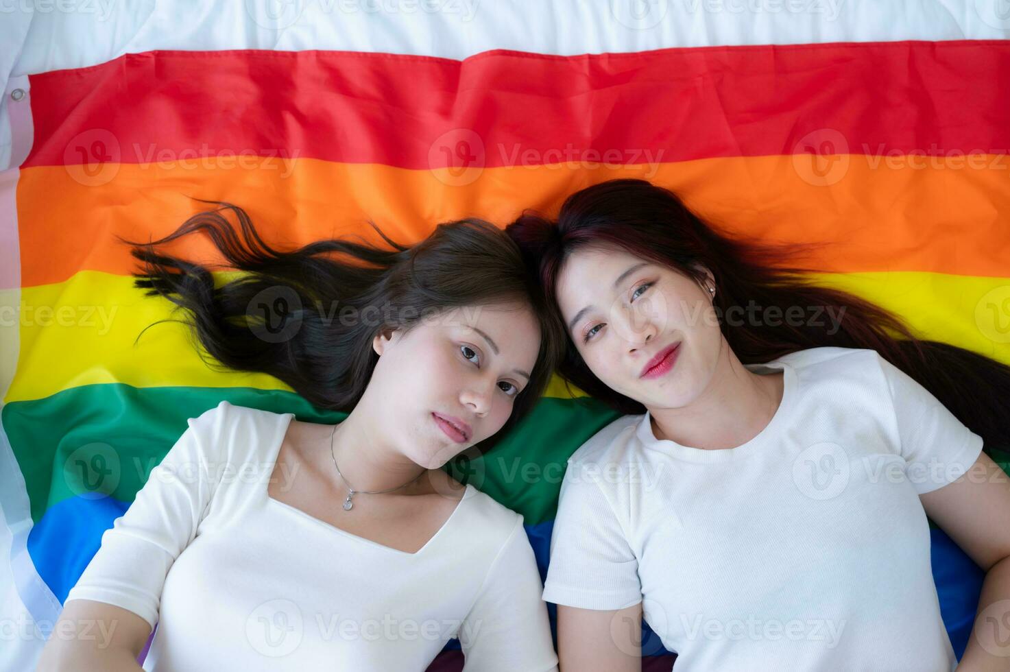 en un arco iris bandera, un lgbt parejas felizmente mentira abajo, charlando, y burlas cada otro. foto