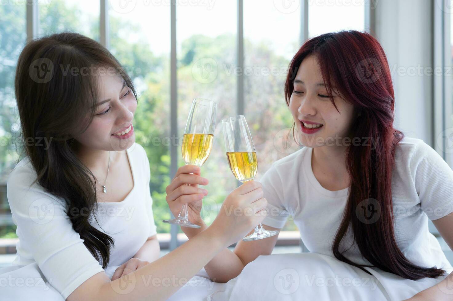 The LGBT couple celebrating with a glass of wine In a hotel room surrounded by nature photo