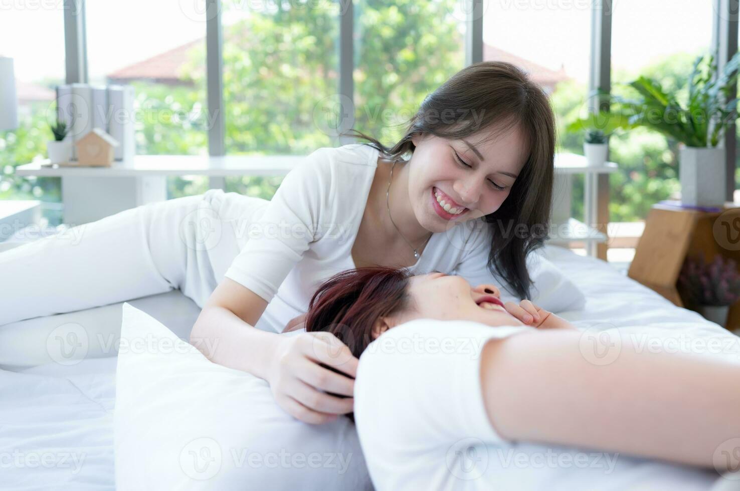 On the white bed, an LGBT couples happily touch and caress each other photo