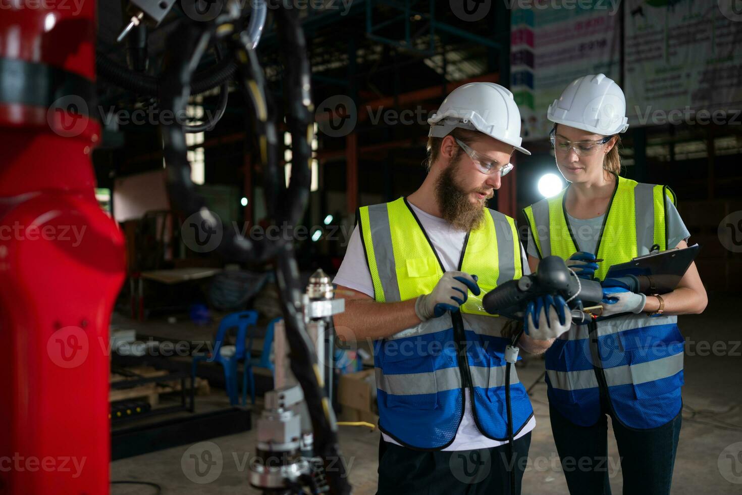 Both of engineers installing and testing a large robotic arm. before sending it to customers for use in the industry photo