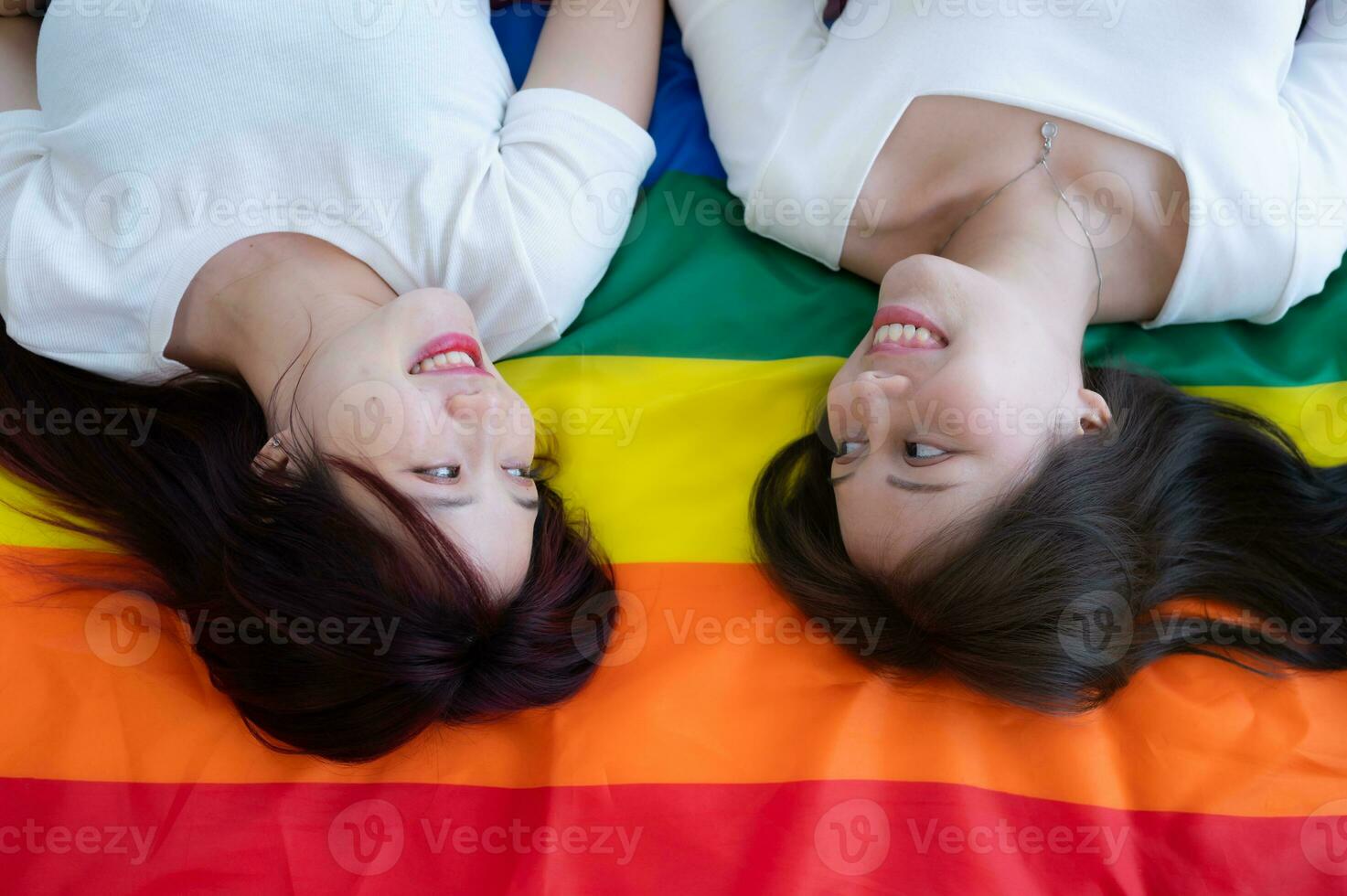 en un arco iris bandera, un lgbt parejas felizmente mentira abajo, charlando, y burlas cada otro. foto