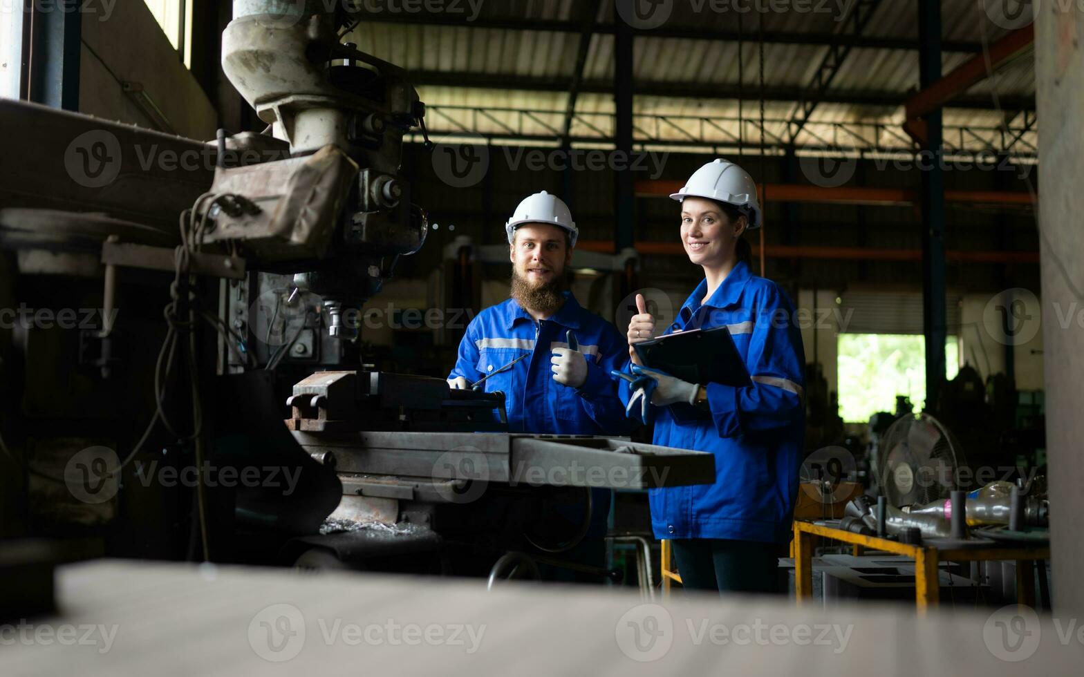 Both of mechanical engineers are checking the working condition of an old machine that has been used for some time. In a factory where natural light shines onto the workplace photo