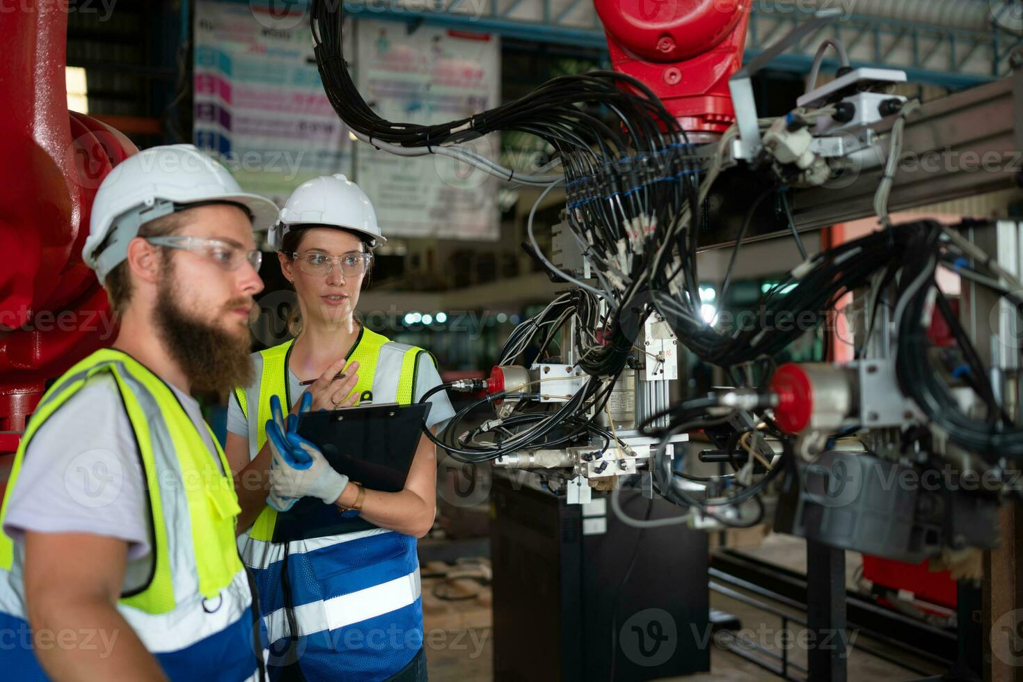 Both of engineers installing and testing a large robotic arm. before sending it to customers for use in the industry photo