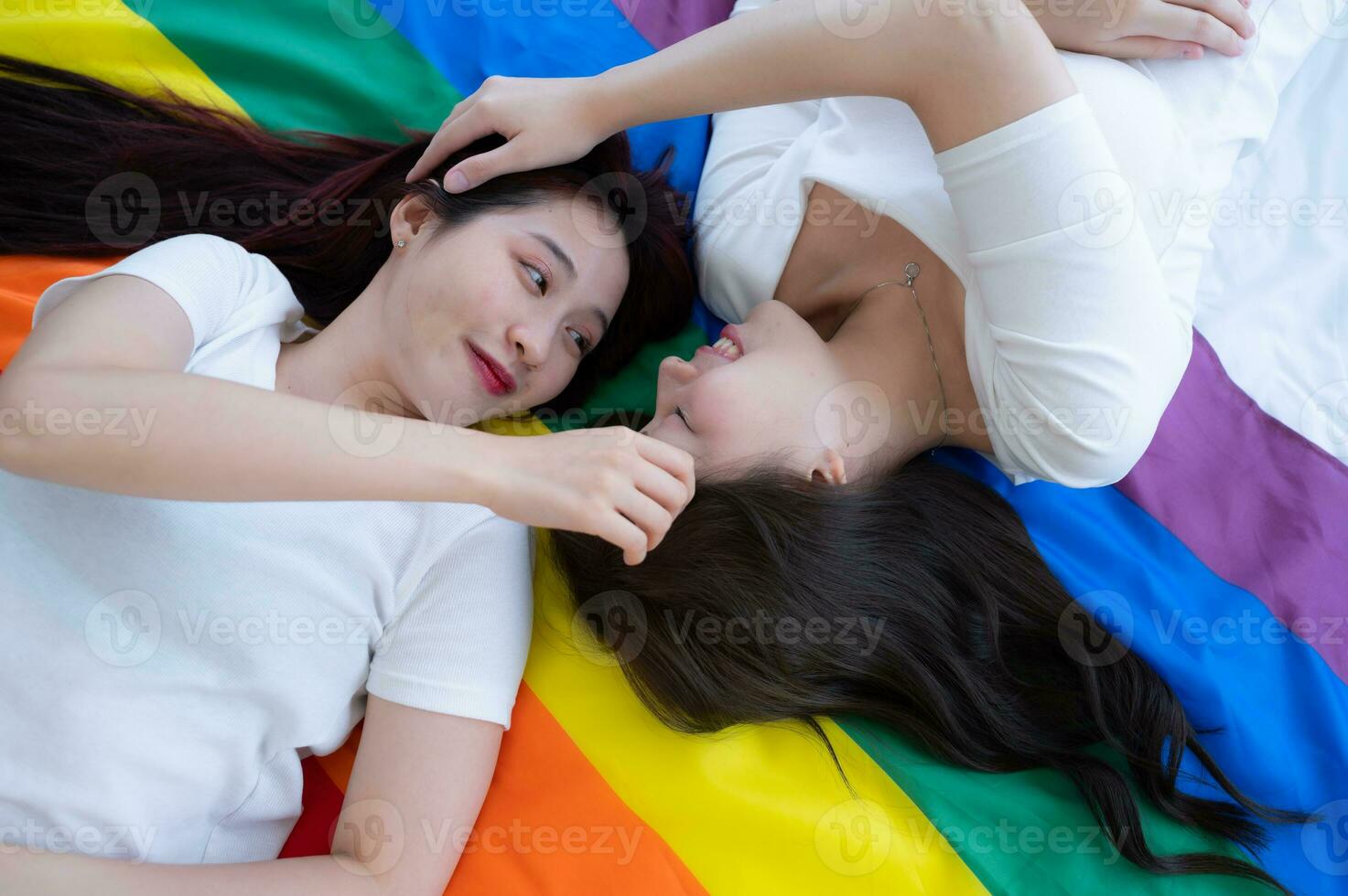 On a rainbow flag, an LGBT couples happily touch and caress each other photo