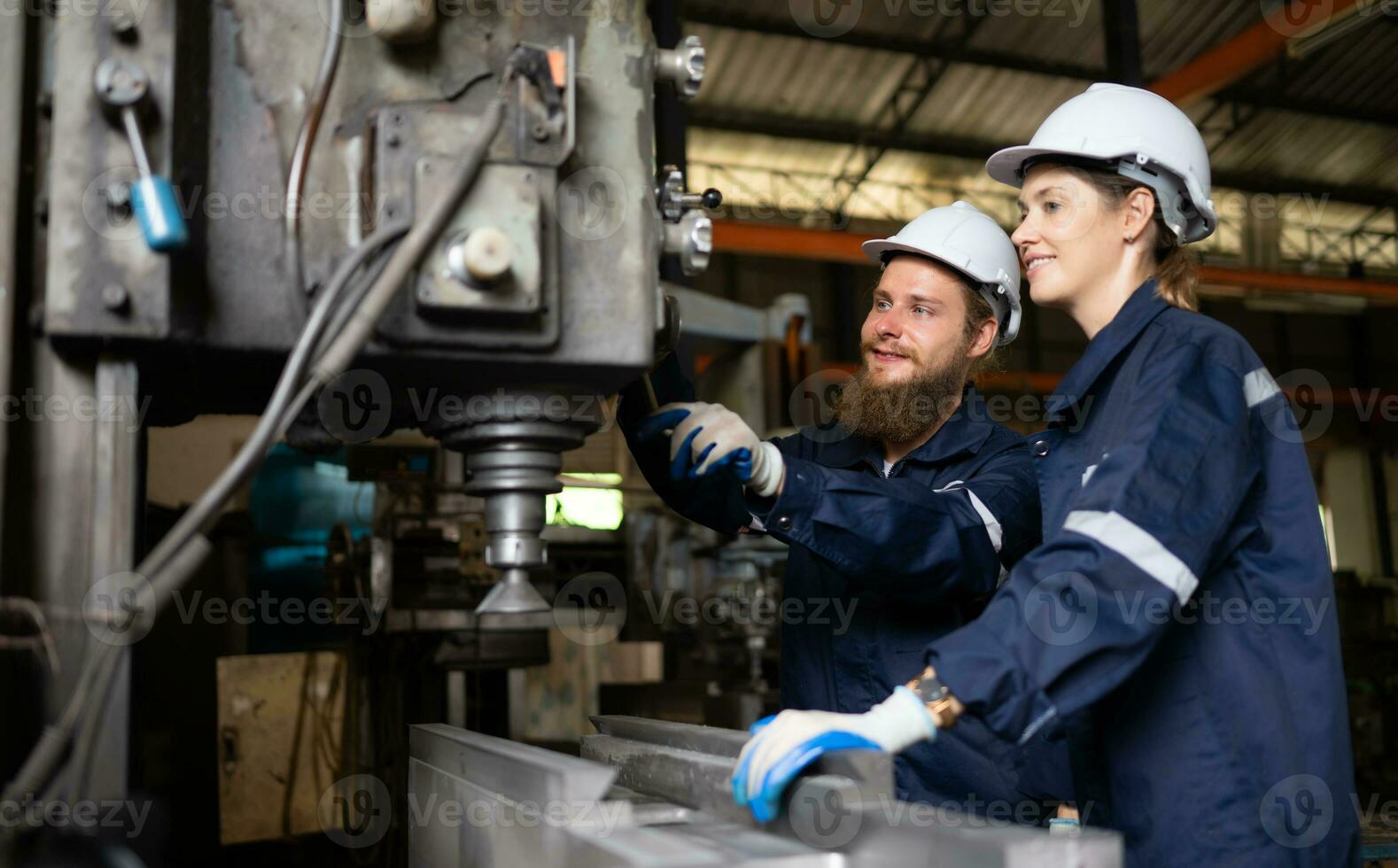 Both of mechanical engineers are checking the working condition of an old machine that has been used for some time. In a factory where natural light shines onto the workplace photo