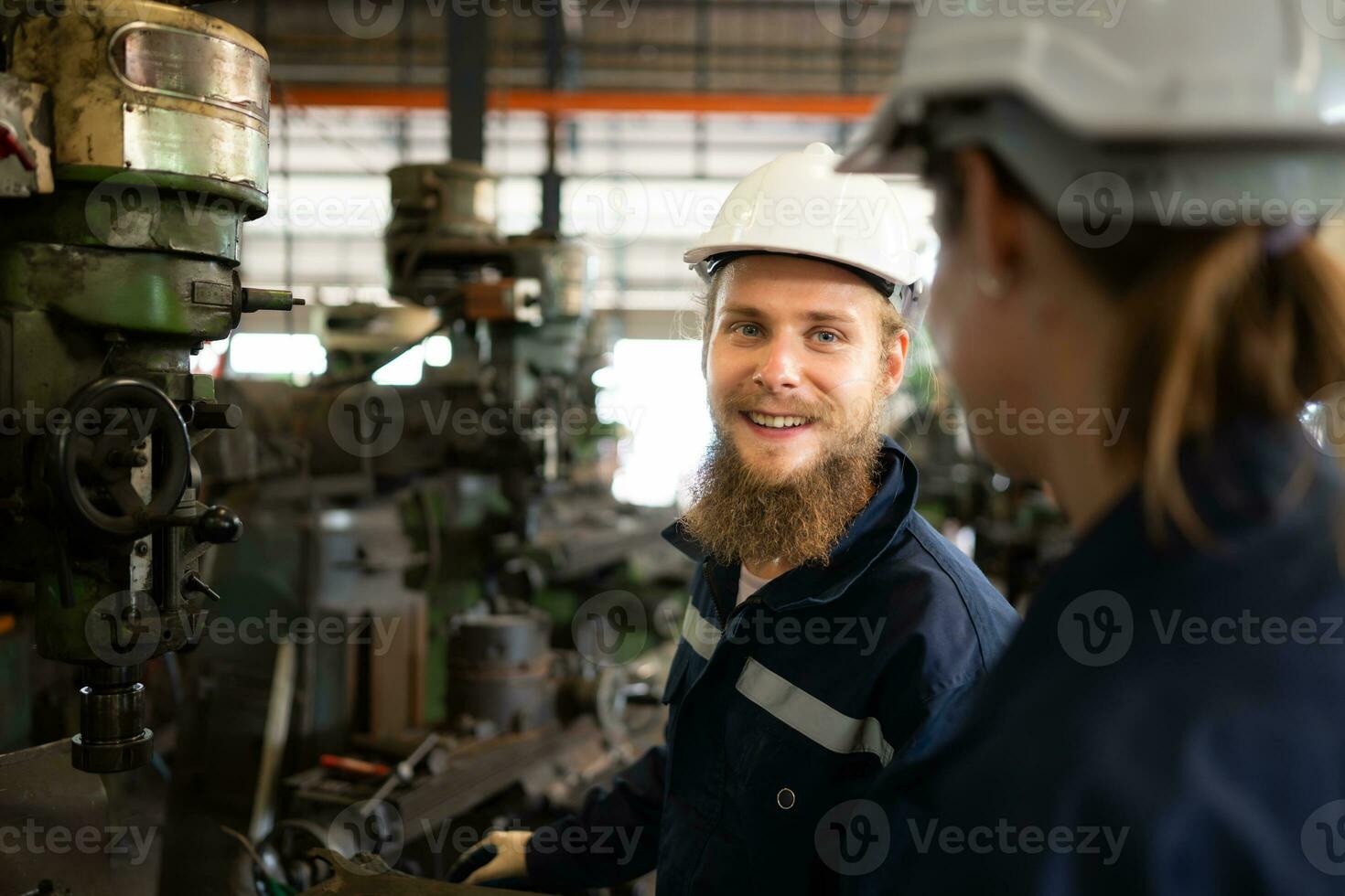 Both of mechanical engineers are checking the working condition of an old machine that has been used for some time. In a factory where natural light shines onto the workplace photo