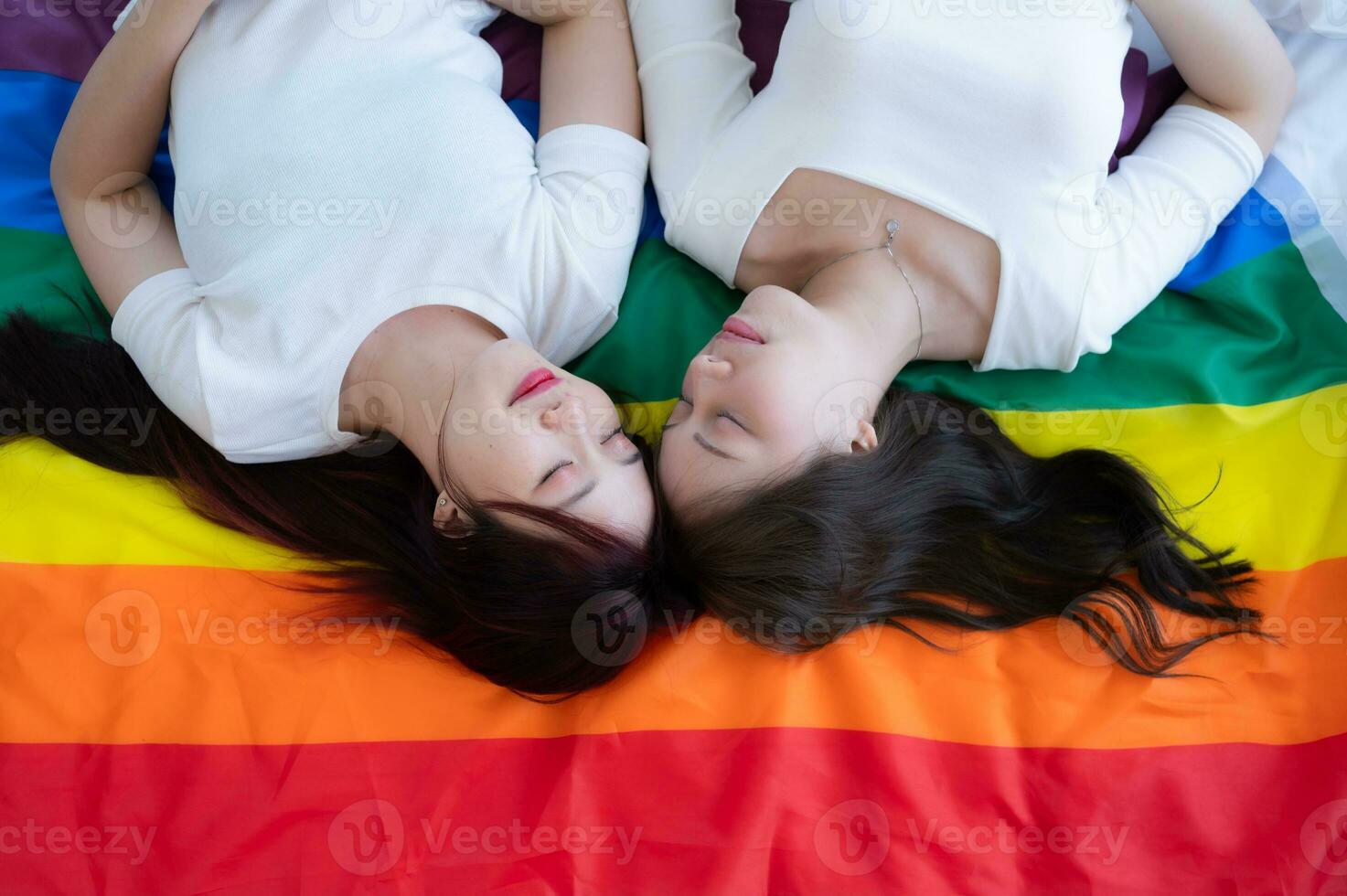 en un arco iris bandera, un lgbt parejas felizmente mentira abajo, charlando, y burlas cada otro. foto