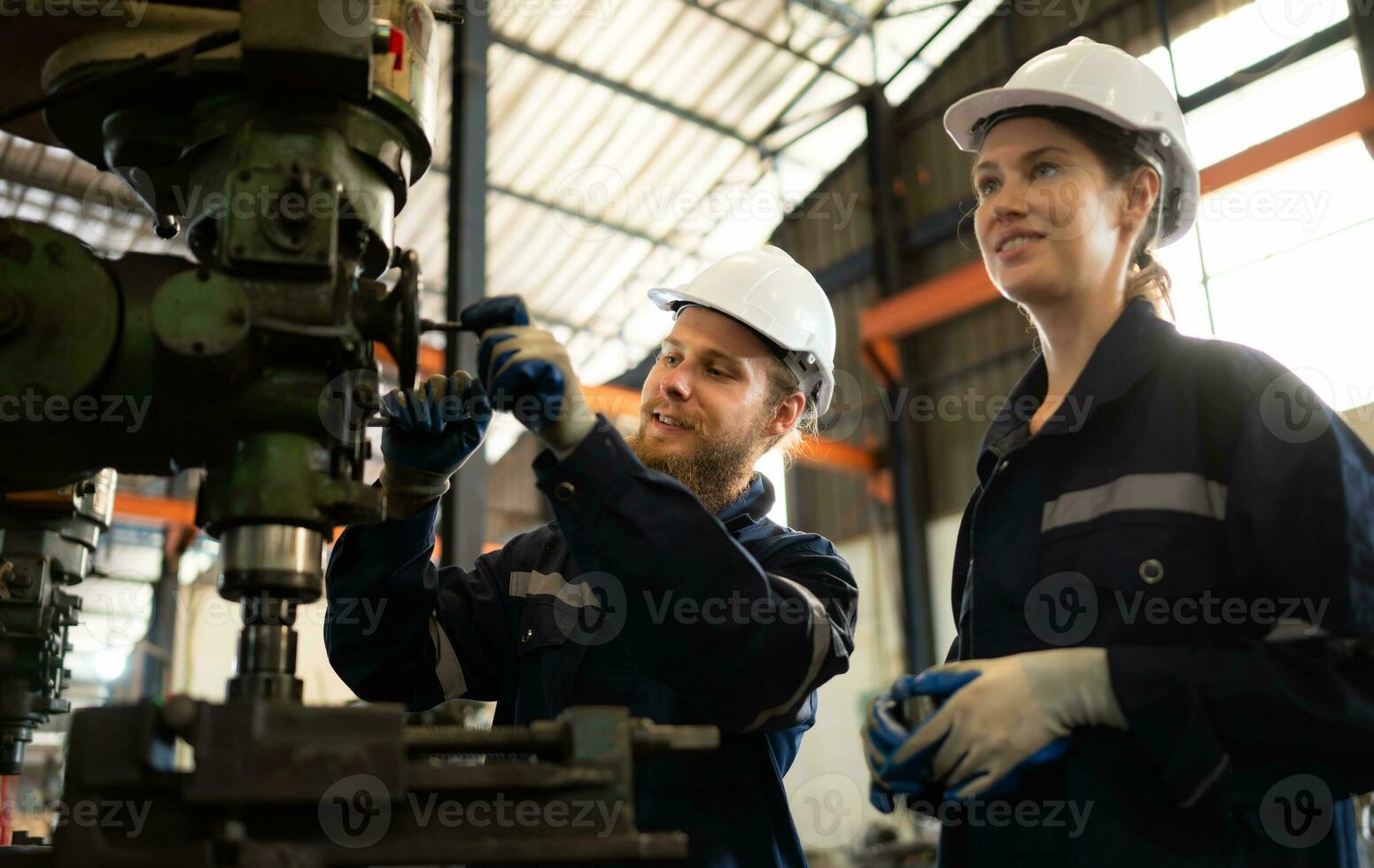 Both of mechanical engineers are checking the working condition of an old machine that has been used for some time. In a factory where natural light shines onto the workplace photo