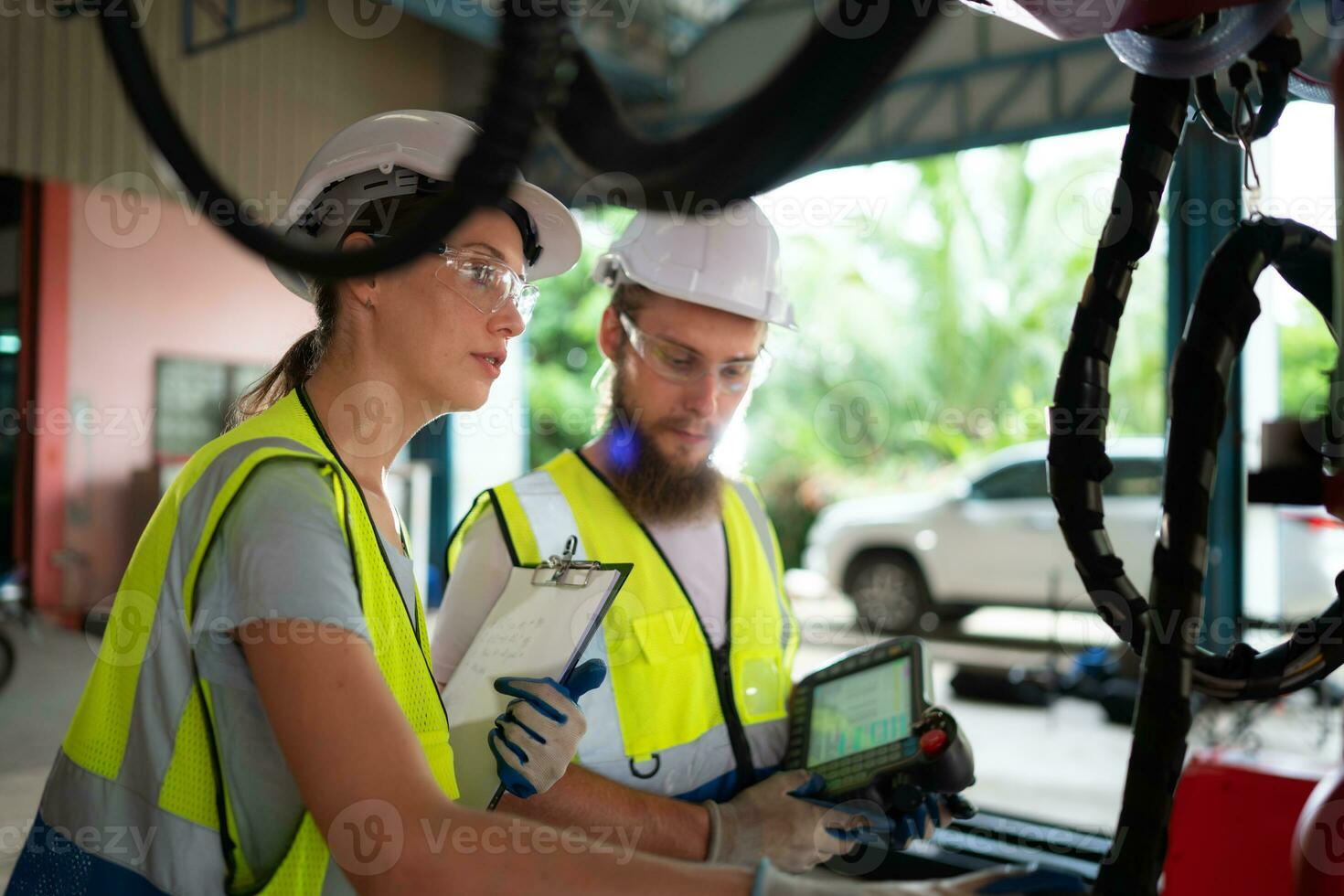 Both of engineers installing and testing a large robotic arm. before sending it to customers for use in the industry photo