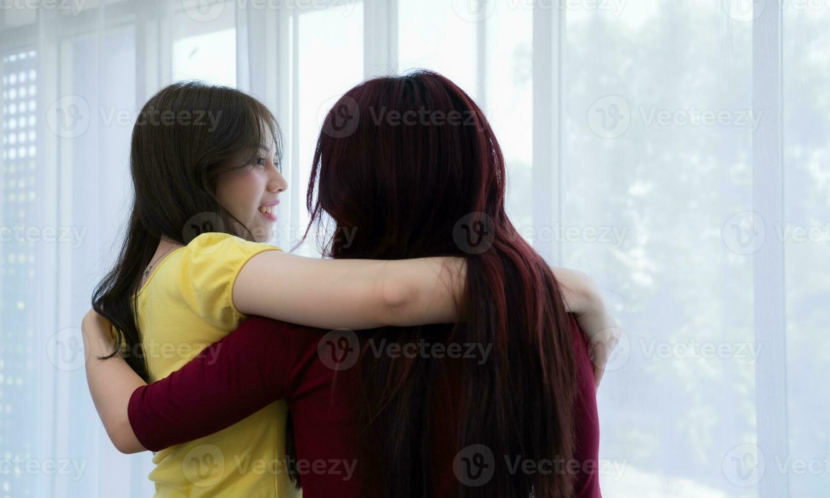 LGBT couples cover rainbow flags around their loved ones to keep warm and gaze out their hotel room windows together. photo