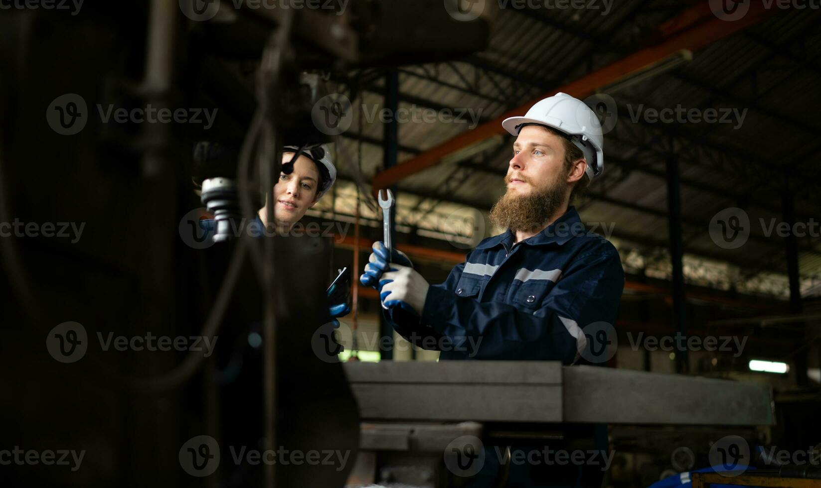 Portrait of mechanical engineers are checking the working condition of an old machine that has been used for some time. In a factory where natural light shines onto the workplace photo
