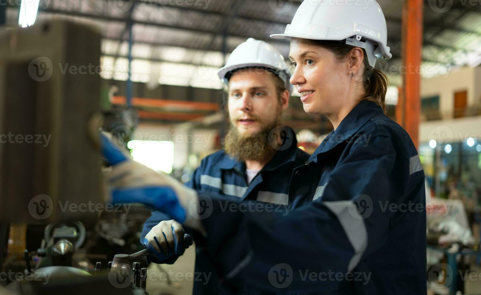 Both of mechanical engineers are checking the working condition of an old machine that has been used for some time. In a factory where natural light shines onto the workplace photo