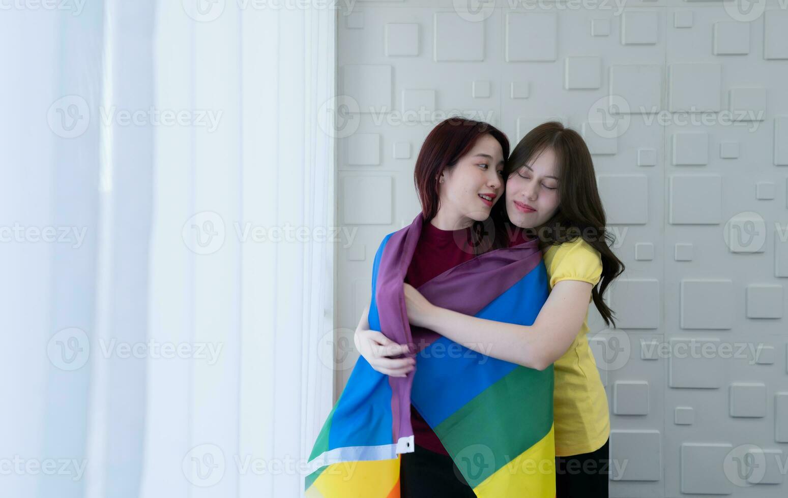 LGBT couples cover rainbow flags around their loved ones to keep warm and gaze out their hotel room windows together. photo