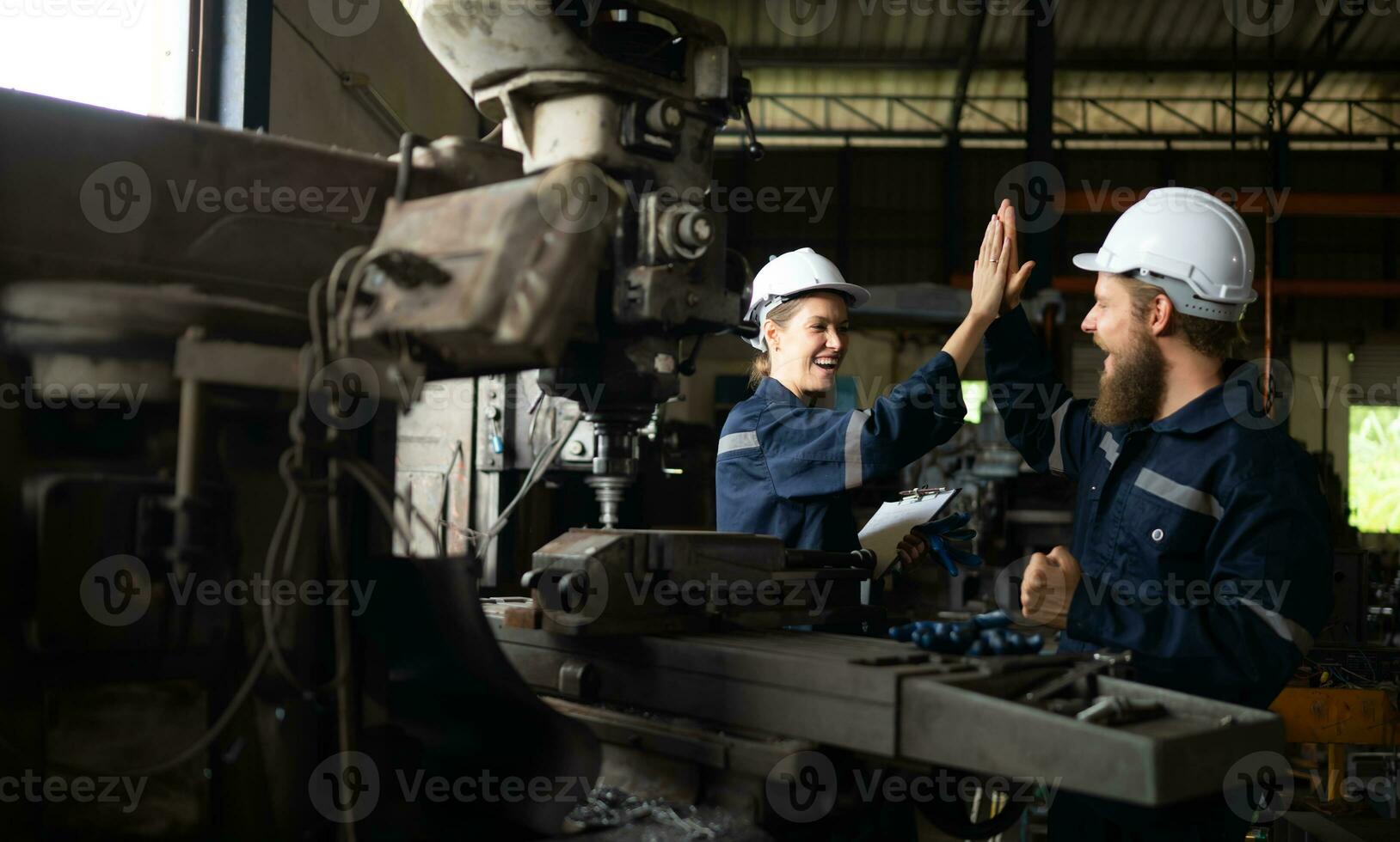 Both of mechanical engineers are checking the working condition of an old machine that has been used for some time. In a factory where natural light shines onto the workplace photo