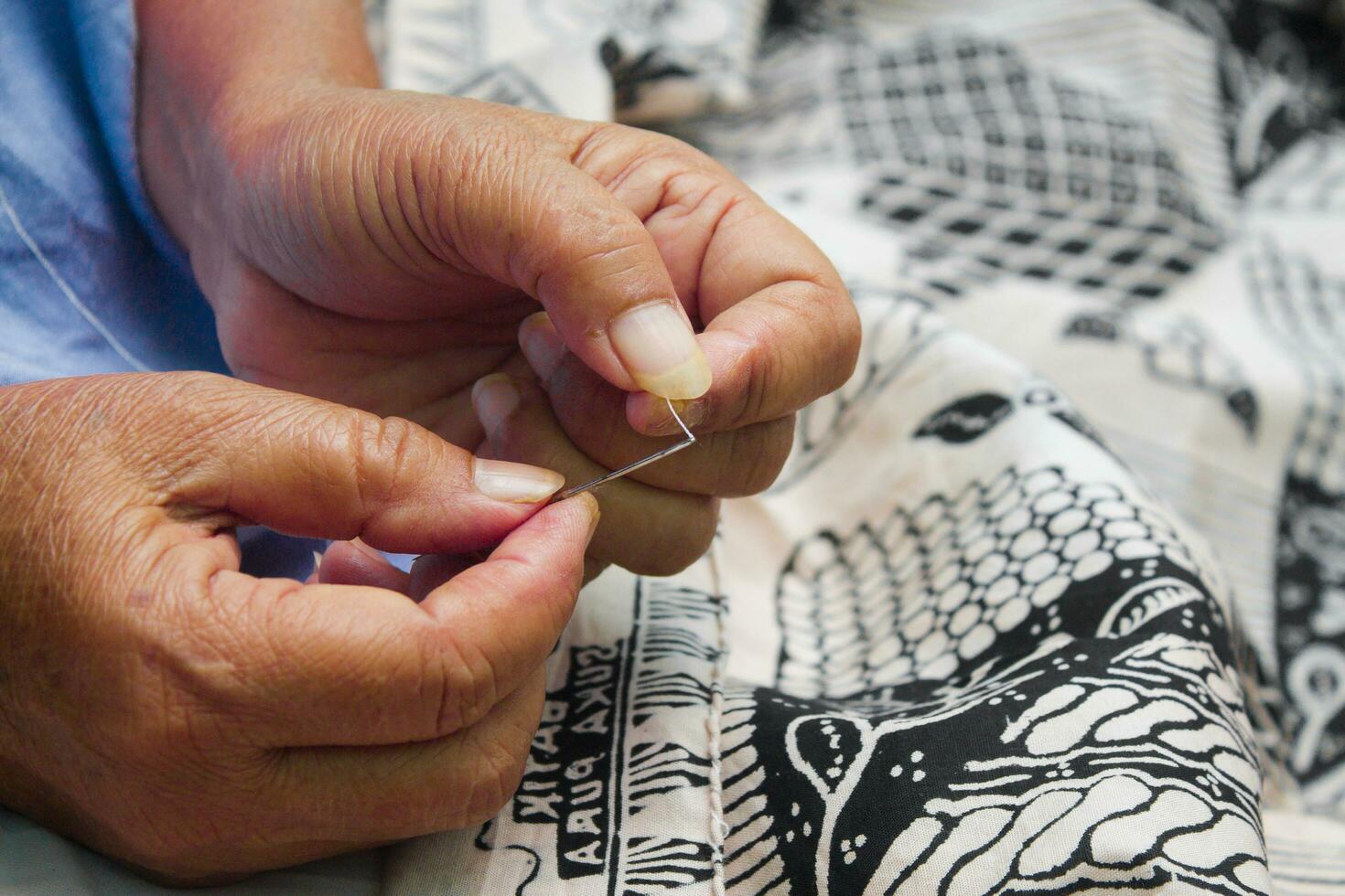 Close up photo of a woman's hands sewing batik cloth in Indonesia