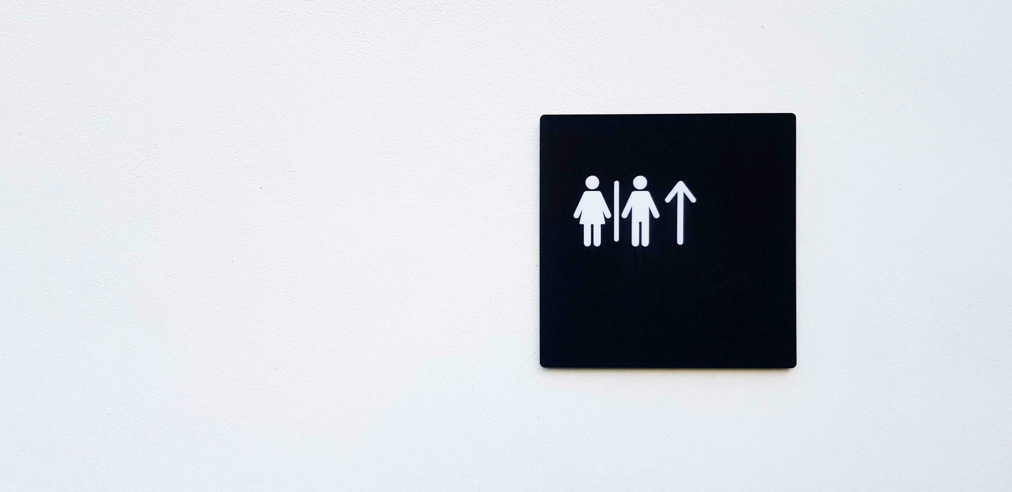 Restroom, toilet or washroom sign or symbol on white wall and give direction and way to go straight with copy space photo