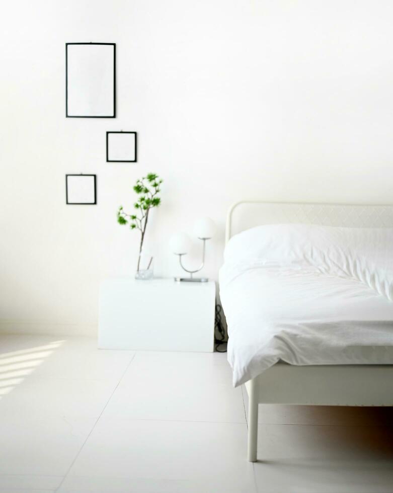 Modern bedroom with white bed, lamp and green ornamental and picture frame for mockup on wall with copy space. Selective focus on soft blanket. Interior design and Comfortable room for sleep and relax photo