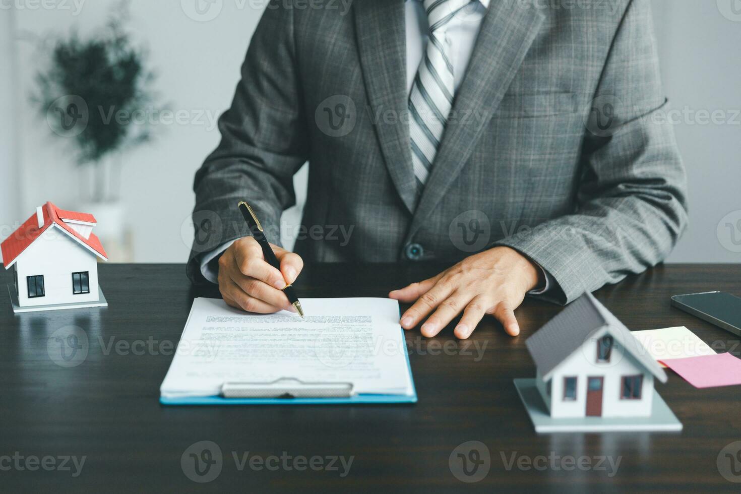Property insurance and security concept. Protecting gesture of man and symbol of house. Estate agent giving house keys to woman and asked customer to sign the documents to make the contract legally. photo