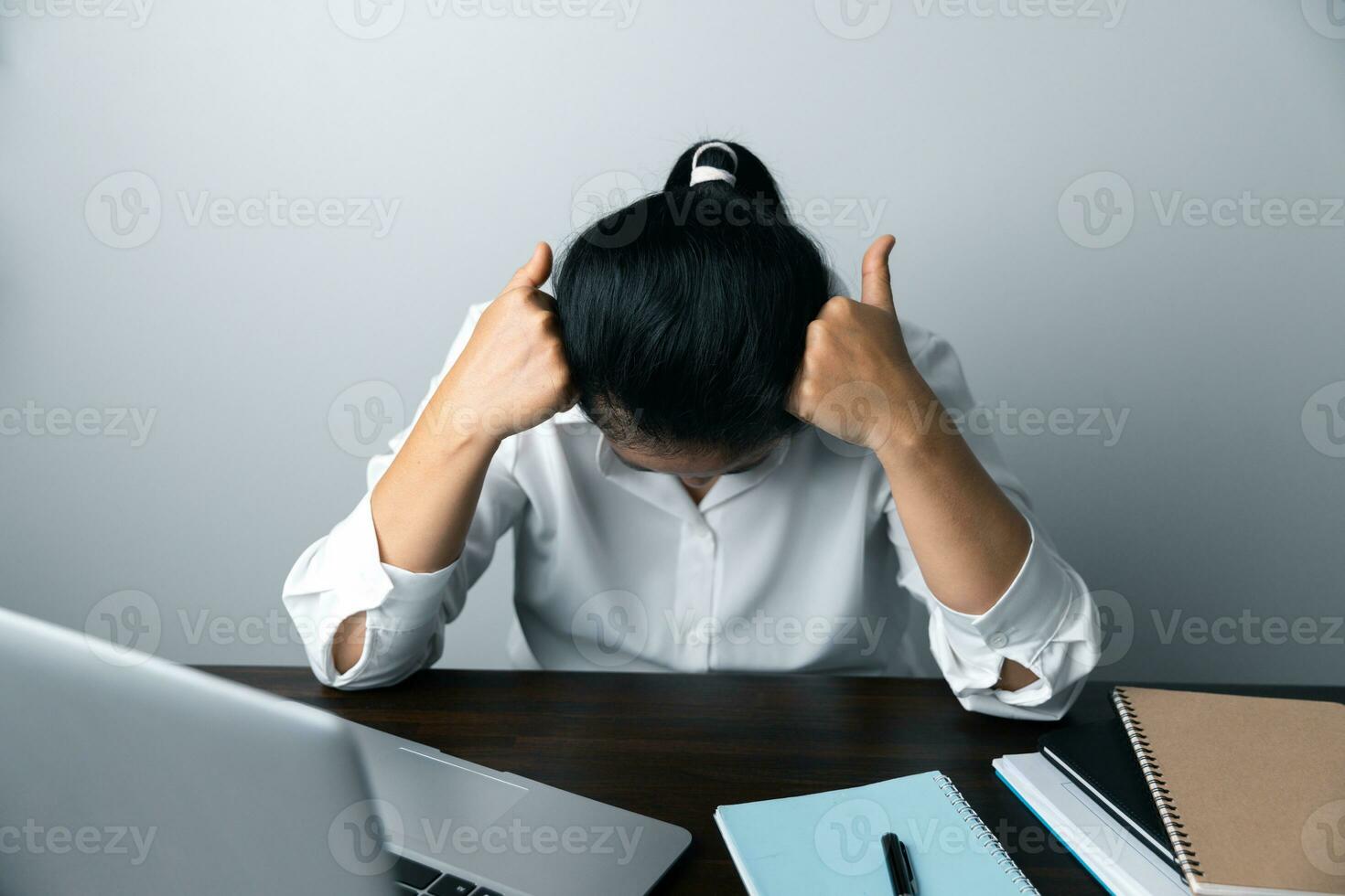 A business office worker is an asian woman is sitting in front of the laptop computer. A businesswoman stressing her body part fingers, hands arm. A femaleOffice manager is exhausted at her workplace. photo