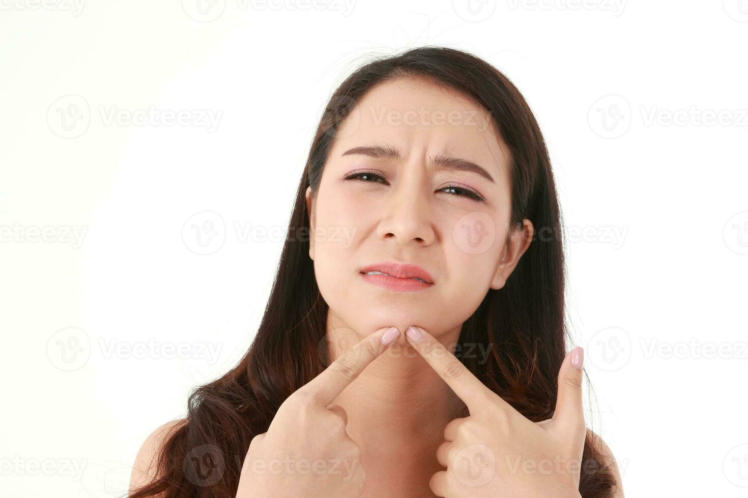 A beautiful woman with long hair Asian has acne on her face. She used her hand to squeeze the pimple on her chin, feeling pain. Beauty concept. Taking care of your face to be beautiful. acne treatment photo