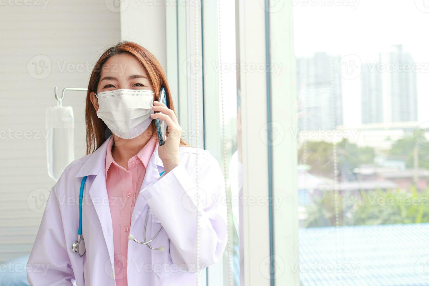 Beautiful Asian female doctor wearing a white mask Hold a smartphone and talk to the patient. Modern communication technology concept, patient care through smartphone. copy space photo