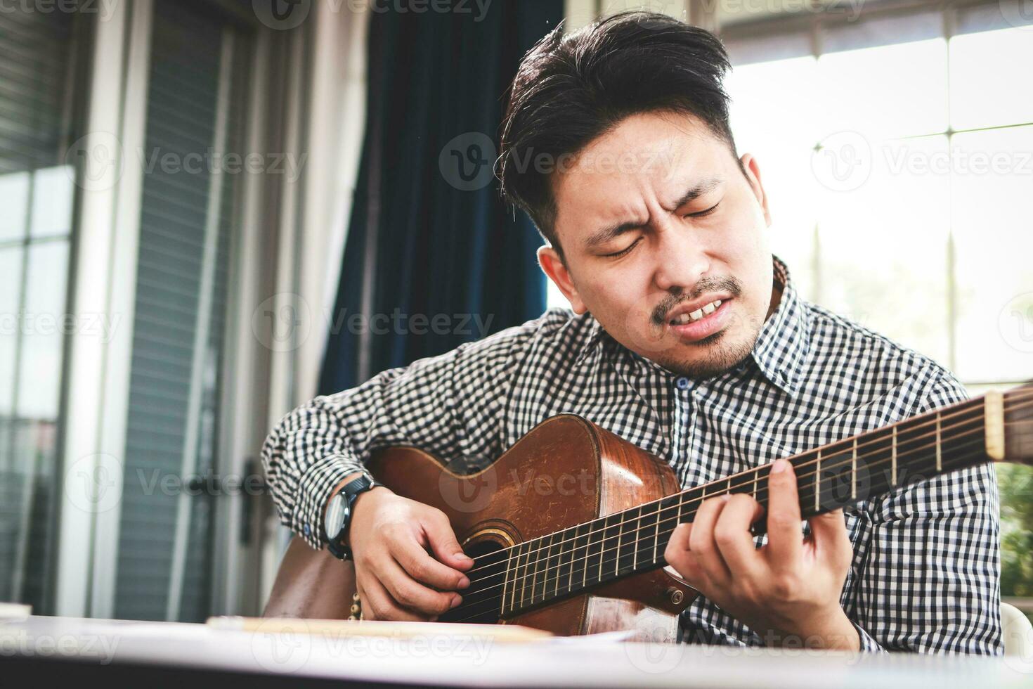 Asian male musician playing guitar in recording studio. playing live music Acoustic music or classical music genre. Solo artist. composer photo