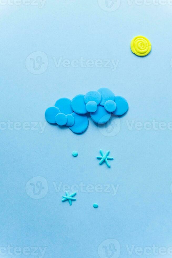 Plasticine sun with cloud and snow. Modeling clay handmade weather on blue background. photo