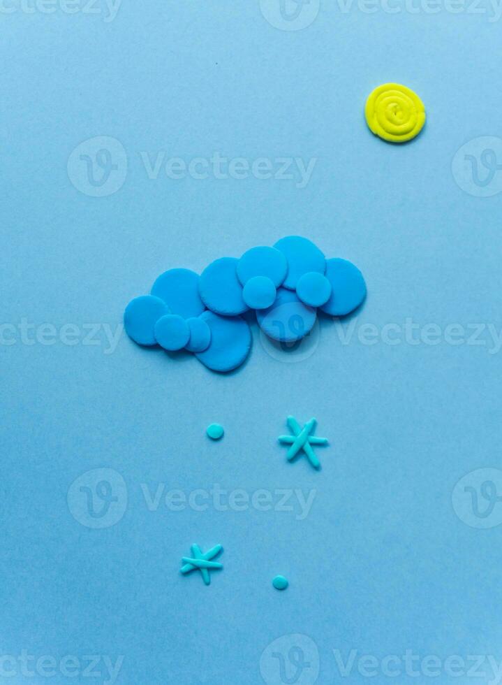 Plasticine sun with cloud and snow. Modeling clay handmade weather on blue background. photo