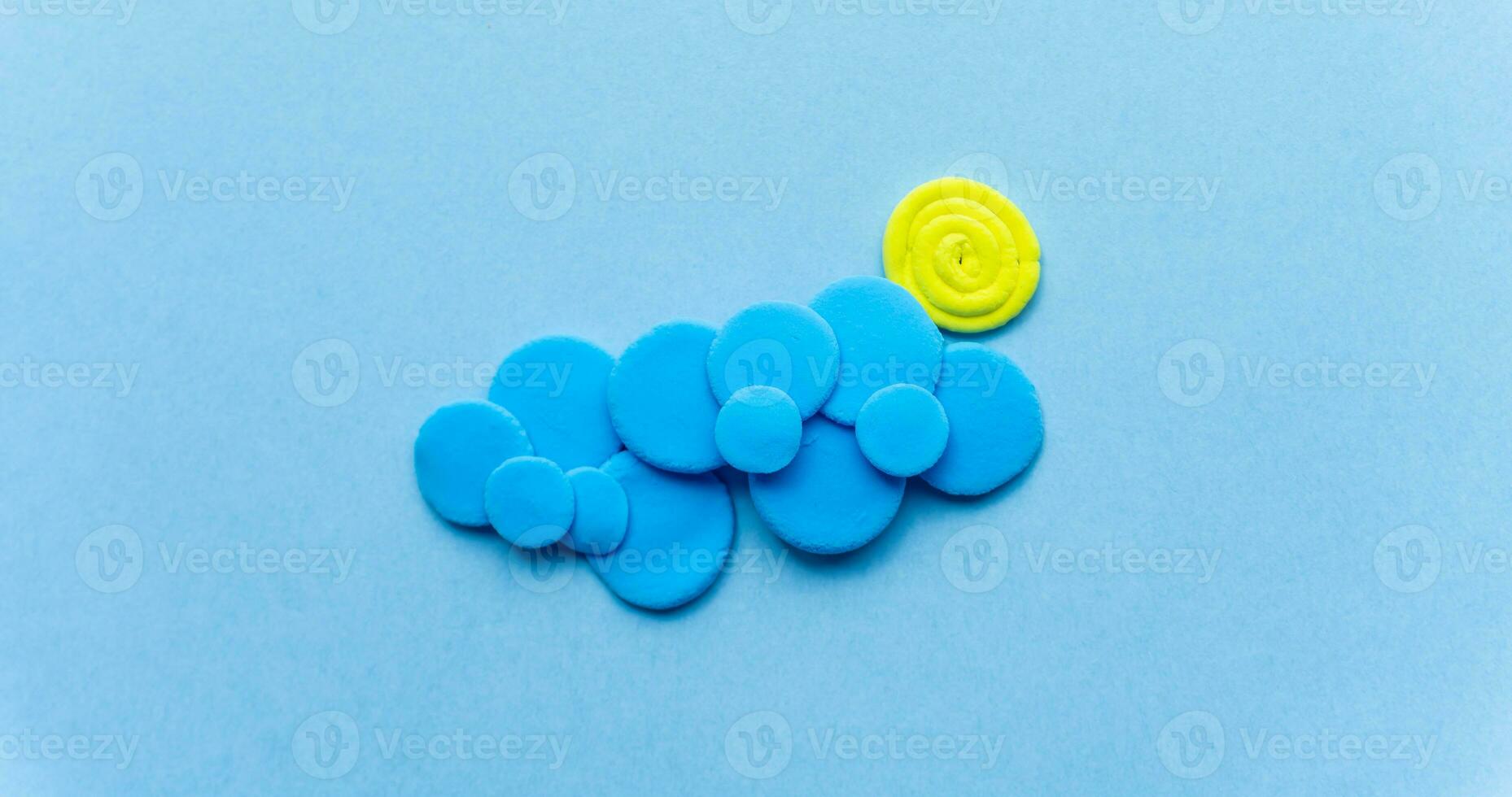 Plasticine sun with cloud. Modeling clay handmade weather on blue background photo