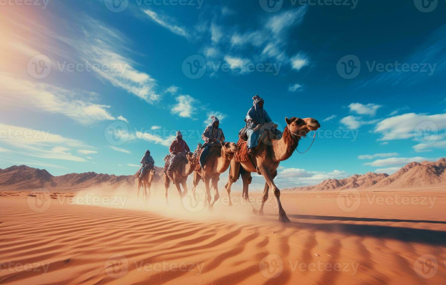People riding camels on a sand dune in the desert photo