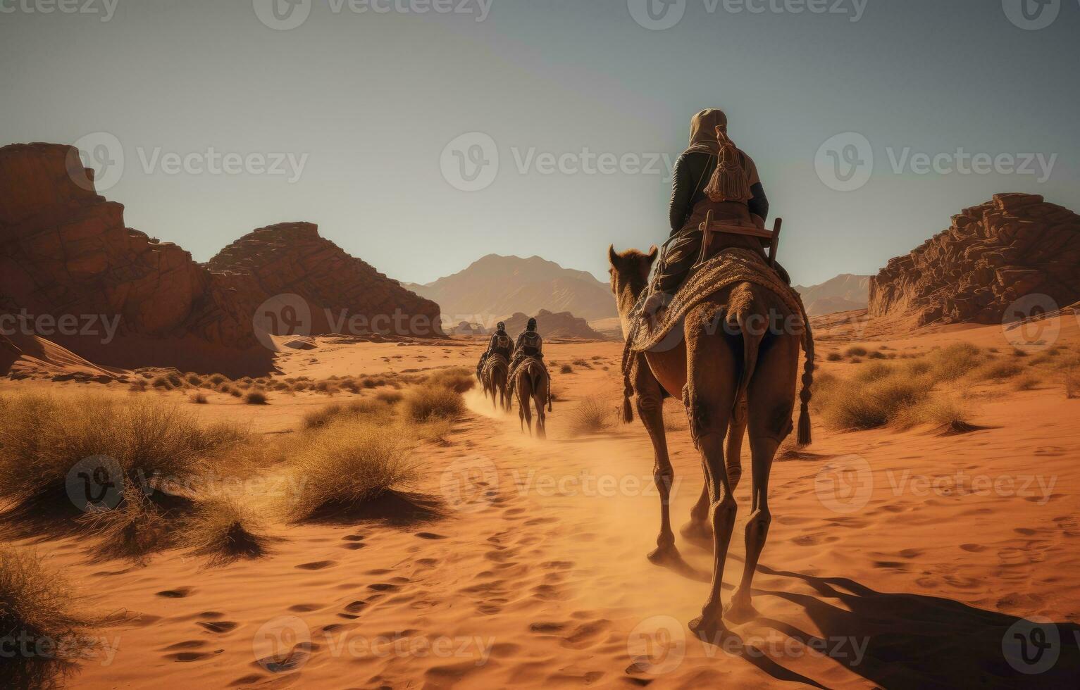 People riding camels on a sand dune in the desert photo