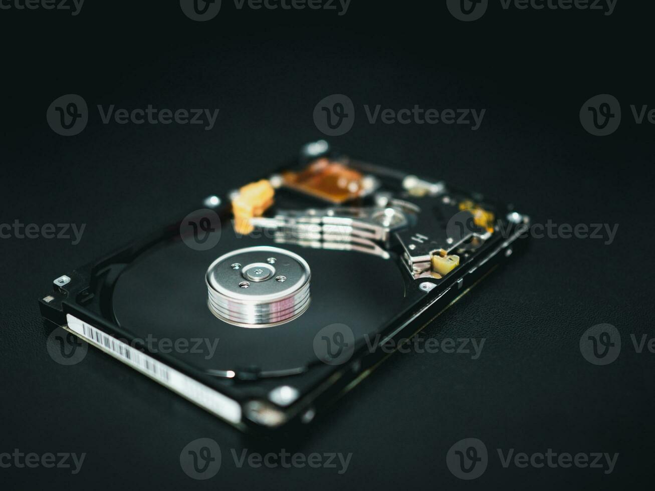 Disassembled open hard disk drive HDD of computer or laptop lies on dark matte surface. photo