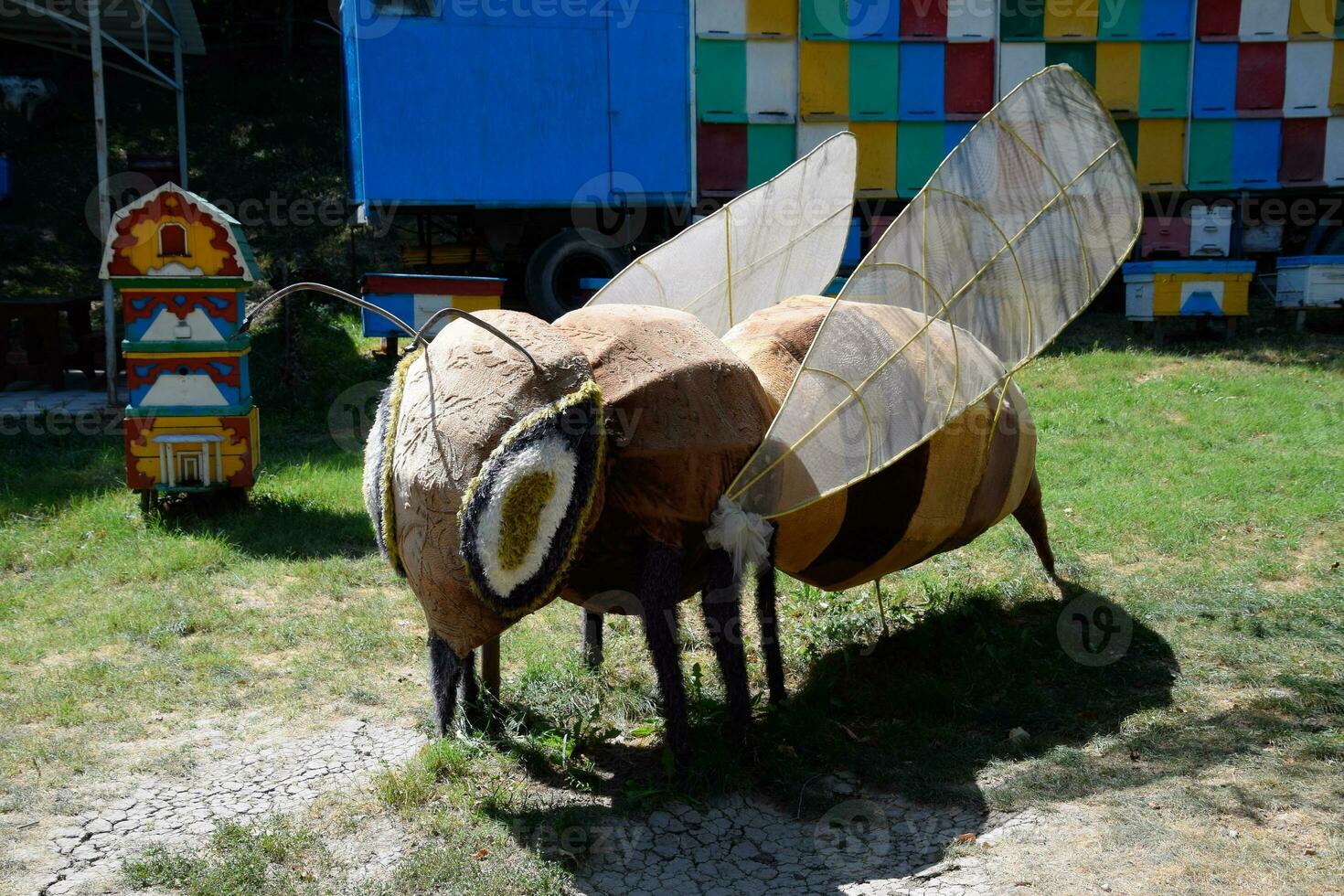 A statue of a bee made of soft material on the lawn near the apiary. photo