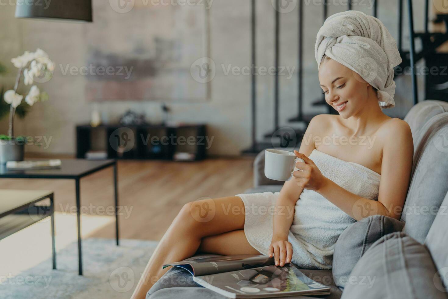 Relaxed woman with healthy skin enjoys home time. Reading magazine, sipping coffee, wrapped in towels. Refreshing spa leisure. photo