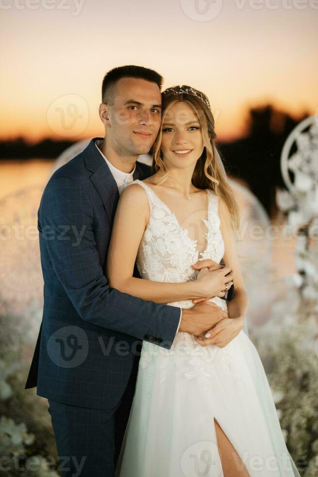 novia y novio contra el telón de fondo de una puesta de sol amarilla foto